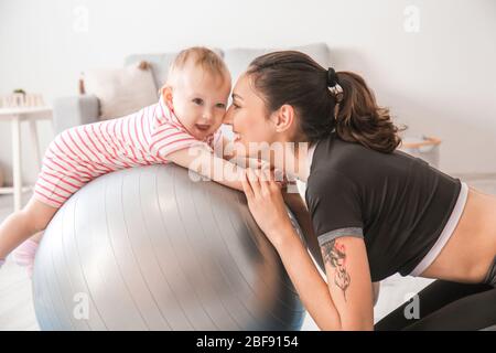 Giovane madre sportiva e il suo bambino che fa esercizi con il fitness a casa Foto Stock