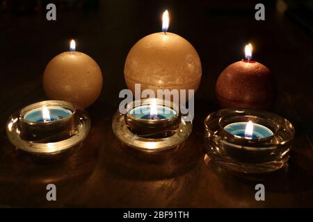 Tre candele sferiche su un tavolo di legno Foto Stock