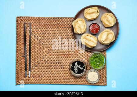 Piatto con gnocchi orientali e salse su fondo colorato Foto Stock