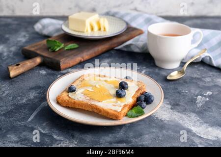 Gustoso pane tostato con miele, burro e frutti di bosco a tavola Foto Stock