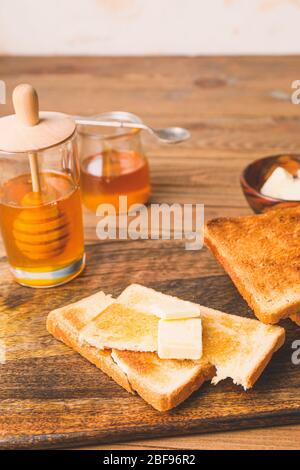 Gustoso pane tostato con miele e burro a tavola Foto Stock