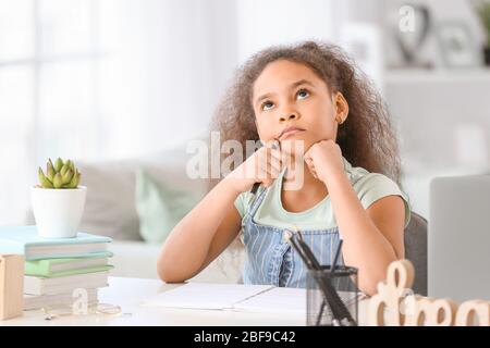 Ragazza afro-americana pensierosa che fa i compiti in camera Foto Stock