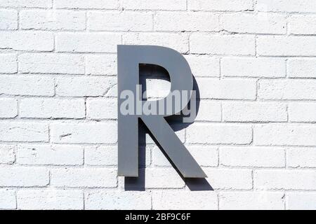 La lettera R come lettera maiuscola su un muro di mattoni bianchi Foto Stock