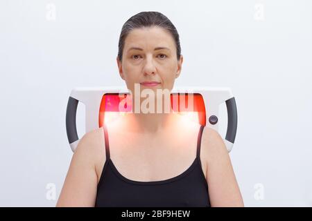 Dolore per un paziente fibromialgia con lampada a luce infrarossa, trattamento termico. Foto Stock