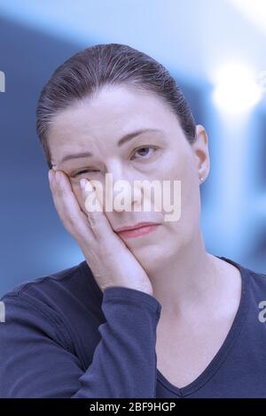 Fibromialgia sintomo affaticamento: Donna molto stanca quasi addormentata in ufficio, effetto filtro blu Foto Stock