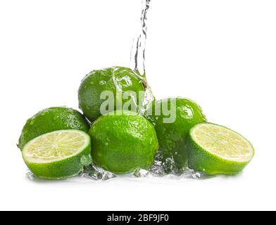 Acqua che si versa su lime fresche su sfondo bianco Foto Stock