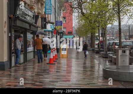 Cork, Irlanda. 17 Aprile 2020. Forte pioggia a Cork City. Coda per il mercato inglese. Una città vuota di Cork oggi sia dalla chiusura che dalle previsioni di pioggia pesante durante il giorno, chiunque che abbia dovuto sfidare la città oggi è stato incontrato con le docce torrenziali. Credit: Damian Coleman/Alamy Live News Foto Stock