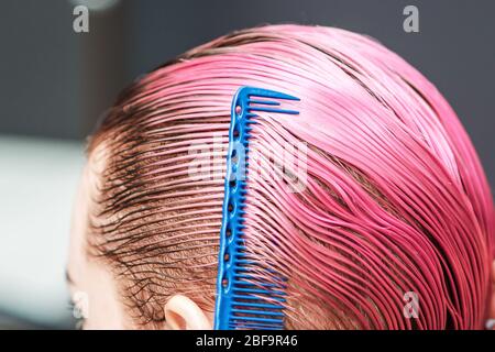 La mano del parrucchiere sta pettinando i capelli corti ed bagnati della donna nel salone di capelli, primo piano in su. Foto Stock