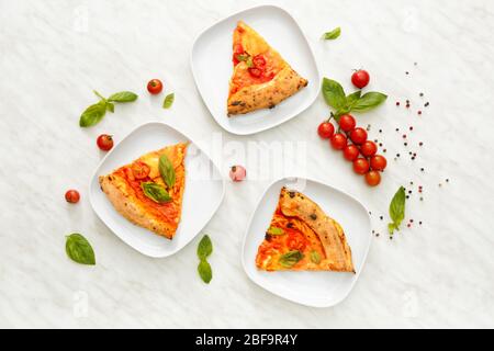Piatti a fette di deliziosa pizza Margherita a tavola Foto Stock