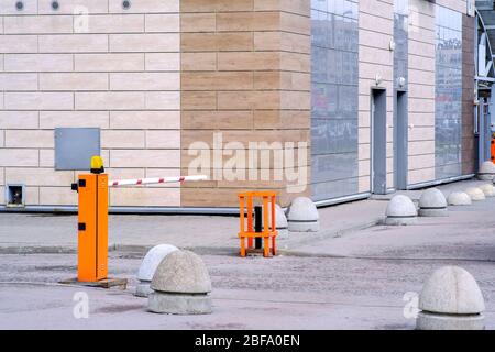 Barriera automatica di colore arancione con una striscia bianca e strisce rosse di segnalazione, per l'ingresso delle vetture. Ingresso al cortile di una residenza d'elite Foto Stock