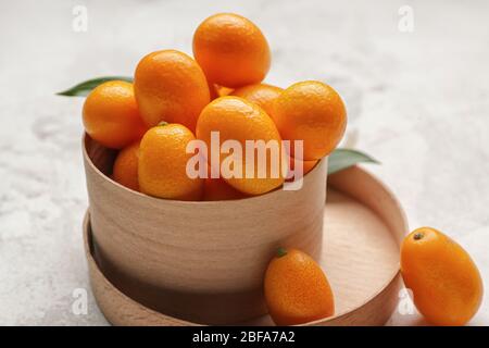 Scatola con gustosa frutta kumquat su sfondo bianco Foto Stock
