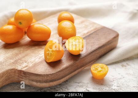Tavola con gustoso kumquat frutta su sfondo bianco Foto Stock