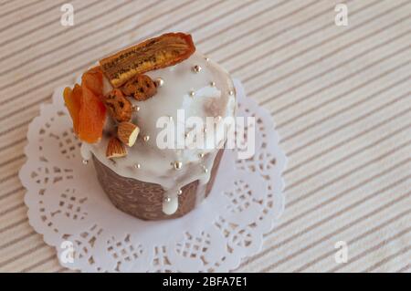 Vista dall'alto del tradizionale kulich pasquale ortodosso. Torta elegante e deliziosa sul tovagliolo bianco con dettagli di taglio decorati da banane secche, albicocche, Foto Stock