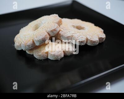 Tre biscotti su un piatto nero, tre biscotti fatti in casa Canestrelli Foto Stock