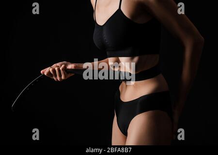 Donna malata stringendo la vita con cintura su sfondo scuro. Concetto di anoressia Foto Stock