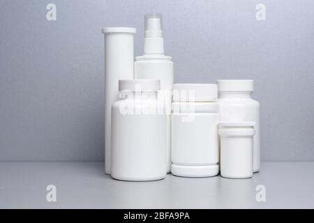 6 vasetti bianchi per medicinali e vitamine e integratori alimentari senza nome sono su una mensola grigia. Foto Stock