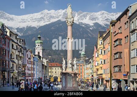 Innsbruck, Austria - 2 marzo 2011: Persone non identificate nella zona di quartiere di via Maria Theresien con colonna Anna, torre della chiesa dell'ospedale e città t Foto Stock