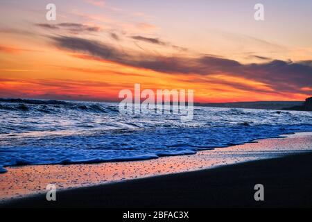 Incredibile tramonto sulla spiaggia con incredibili onde scintillanti. Tramonto e onde di mare sulla spiaggia spettacolare. Blu e giallo infinito Foto Stock