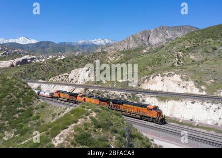 Treno merci che sale al Cajon Pass nella contea di San Bernardino, parte della grande catena logistica della California meridionale Foto Stock