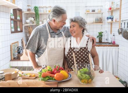 Felice coppia anziana asiatica che cucinano il pasto fresco in cucina a casa. Foto Stock