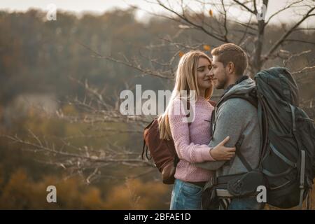 Un paio di viaggiatori sorridenti in piedi abbracciati all'aperto Foto Stock