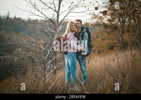 Coppia sorridente con zaini in piedi abbracciati Foto Stock