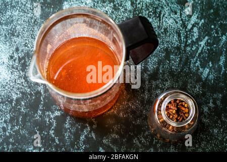 Acqua o tè Sumac e spezie Sumac rosso macinato essiccato con chiodi di garofano in French press. Pronto a bere. Foto Stock