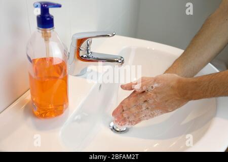 COVID-19 Pandemic Coronavirus uomo lavando le mani sfregando con sapone sotto il rubinetto con acqua contro malattia di Coronavirus 2019. Antisettico, igiene an Foto Stock