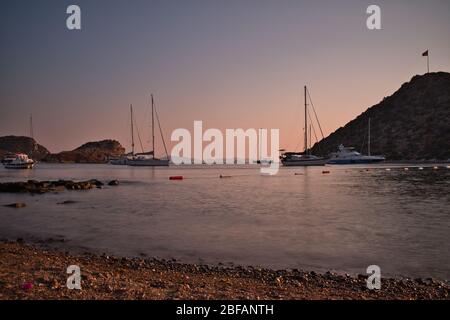 Ristorante e fiori di bougainvillea sulla spiaggia a Gumusluk, Bodrum. Sedie colorate, tavoli e fiori nella città di Bodrum vicino al bellissimo Mar Egeo. Foto Stock