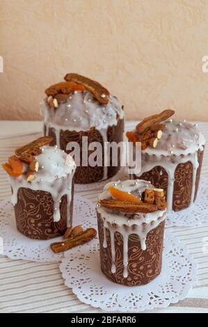 Quattro eleganti dolci tradizionali di Pasqua ortodossi fatti in casa deliziosi sui tovaglioli bianchi decorati da banane secche, albicocche d'arancia, mandorle e piccole Foto Stock