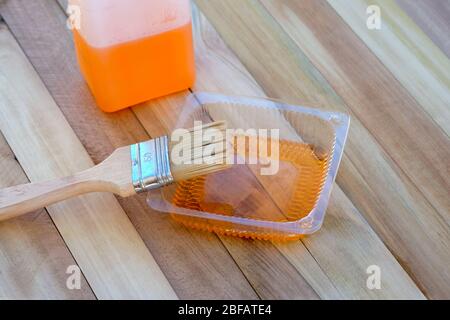 impregnazione per pavimenti in legno con spazzola e contenitore sullo sfondo delle tavole. soluzione speciale per la protezione del legno. impregnazione per legno Foto Stock