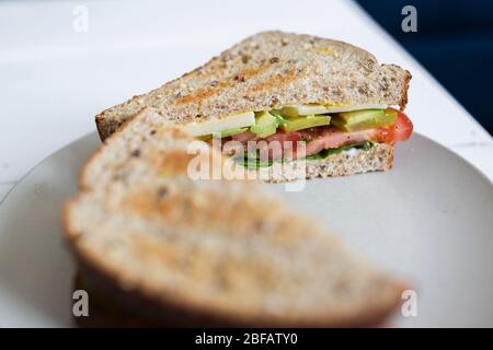 Un sano panino vegetariano su pane integrale si siede su un piatto pronto per il pranzo. Foto Stock