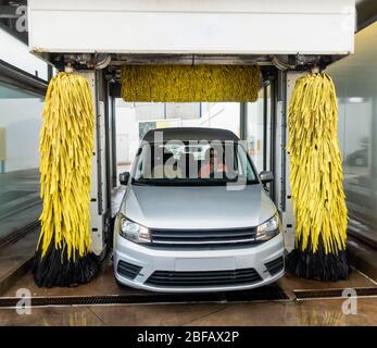 Donna che guida attraverso il lavaggio automatico dell'auto. Foto Stock
