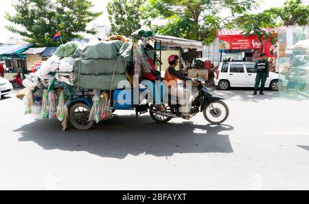 Phnom Penh, Cambogia - Giugno 25,2018: street scene con due venditori di strada su una moto con un sacco di merci. Foto Stock