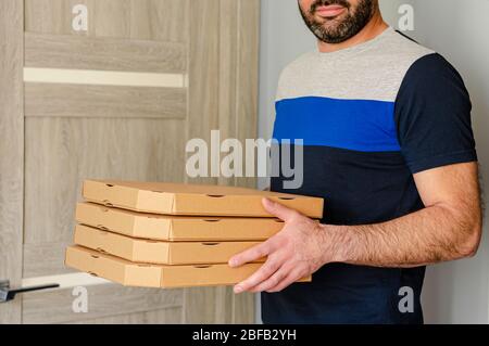 Ritratto corto di uomo bearded sorridente che tiene le scatole della pizza nelle mani. Ordine e consegna dei prodotti alimentari. Foto Stock