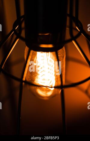Lampadina ad incandescenza Edison arancione vintage in una vecchia lanterna Foto Stock