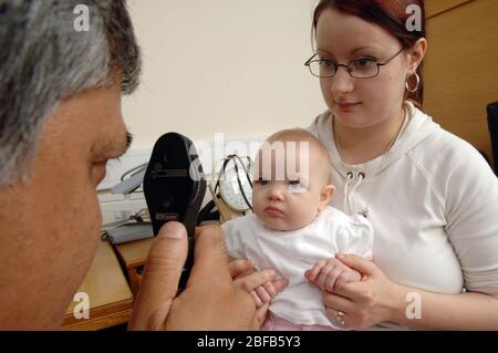 Un GP che utilizza un oftalmoscopio per esaminare la visione di un bambino (modello rilasciato) Foto Stock