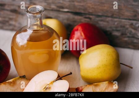 Aceto biologico di mele in caraffa di vetro con mele rosse fresche mature su sfondo di legno. Concetto di cibo biologico sano Foto Stock
