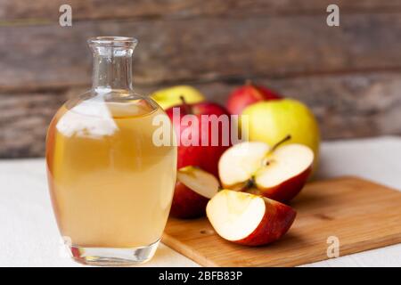 Aceto biologico di mele in caraffa di vetro con mele rosse fresche mature su sfondo di legno. Concetto di cibo biologico sano Foto Stock