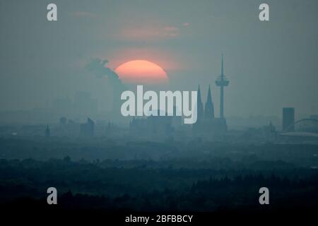 Colonia, Germania. 17 Aprile 2020. Il sole tramonta dietro lo skyline di Colonia. Sullo sfondo si può vedere la centrale elettrica lignite Niederaussem. Credit: Henning Kaiser/dpa/Alamy Live News Foto Stock