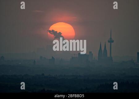 Colonia, Germania. 17 Aprile 2020. Il sole tramonta dietro lo skyline di Colonia. Sullo sfondo si può vedere la centrale elettrica lignite Niederaussem. Credit: Henning Kaiser/dpa/Alamy Live News Foto Stock