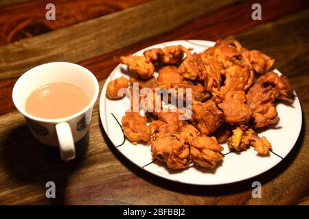Chai con pakora e bhajiya e servito su piatto su sfondo di legno Foto Stock