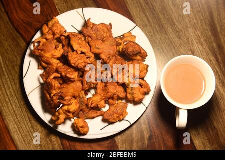 Chai con pakora e bhajiya e servito su piatto su sfondo di legno Foto Stock