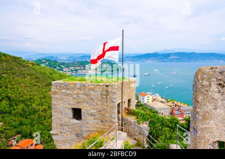 Vista aerea del Golfo di Spezia acque turchesi, antica parete in pietra del Castello Doria torre con bandiera a Portovenere città, Mar Ligure, Rivi Foto Stock