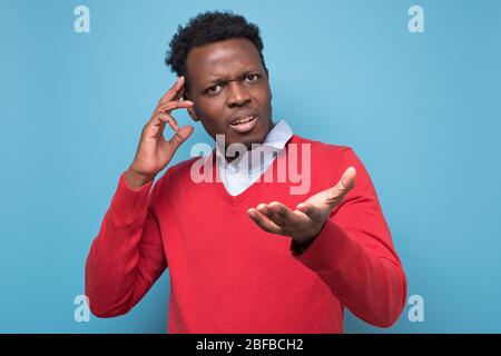 Un giovane africano penoso su sfondo blu Foto Stock