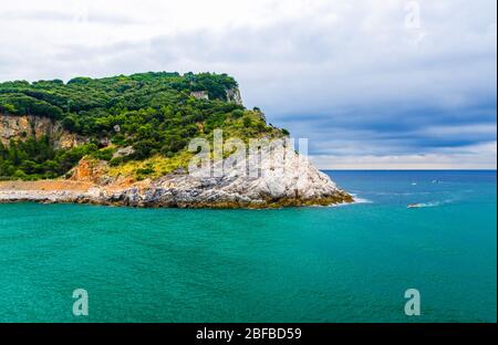 Isola Palmaria con alberi verdi, scogliere, rocce e acque turchesi blu del mare ligure con sfondo cielo drammatico, Riviera di Levante, PA Nazionale Foto Stock