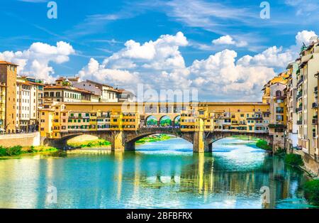 Ponte Vecchio in pietra con edifici colorati, ospita sul fiume Arno acqua turchese blu e passeggiata a banchina nel centro storico di Flore Foto Stock