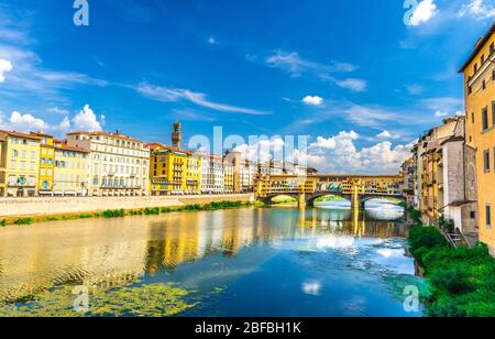 Ponte Vecchio in pietra con edifici colorati, ospita sul fiume Arno acqua turchese blu e passeggiata a banchina nel centro storico di Flore Foto Stock