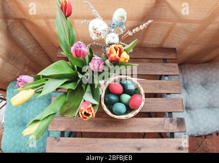 Tavolo in legno con balcone coperto con uova di Pasqua e vaso di fiori tulipano Foto Stock