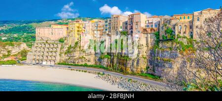 Vista panoramica aerea della città di Tropea e della costa della spiaggia del Mar Tirreno con acque azzurre turchesi, case colorate edifici sulla cima di alto grande ro Foto Stock